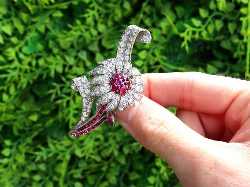 fig 1. A platinum flower brooch featuring diamond-set petals, a cluster of rubies at the centre, and a stem lined with channel-set red rubies.
