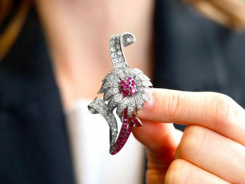 fig 2. A platinum flower brooch featuring diamond-set petals, a cluster of rubies at the centre, and a stem lined with channel-set red rubies.