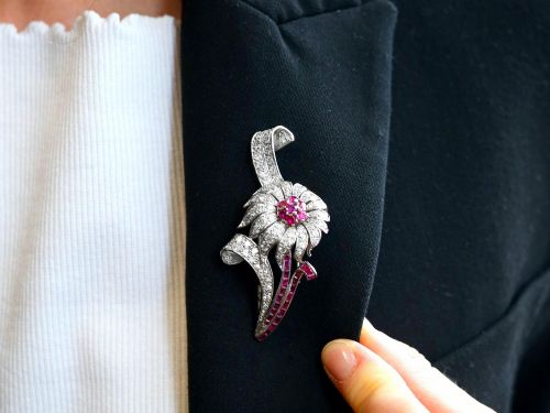 fig 3. A platinum flower brooch featuring diamond-set petals, a cluster of rubies at the centre, and a stem lined with channel-set red rubies.