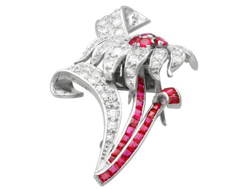 fig 6. A platinum flower brooch featuring diamond-set petals, a cluster of rubies at the centre, and a stem lined with channel-set red rubies.