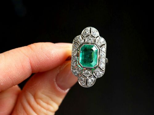 fig 2. An Art Deco platinum dress ring featuring a central rectangular emerald surrounded by an elongated geometric pierced frame set with diamonds.