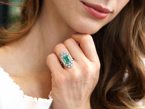 fig 4. An Art Deco platinum dress ring featuring a central rectangular emerald surrounded by an elongated geometric pierced frame set with diamonds.