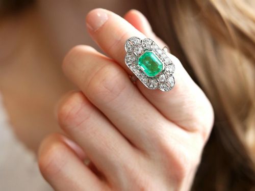 fig 5. An Art Deco platinum dress ring featuring a central rectangular emerald surrounded by an elongated geometric pierced frame set with diamonds.