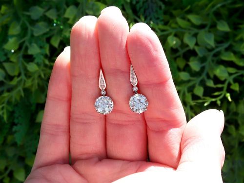 fig 1. A pair of antique diamond drop earrings featuring round diamonds suspended from decorative articulated mounts.