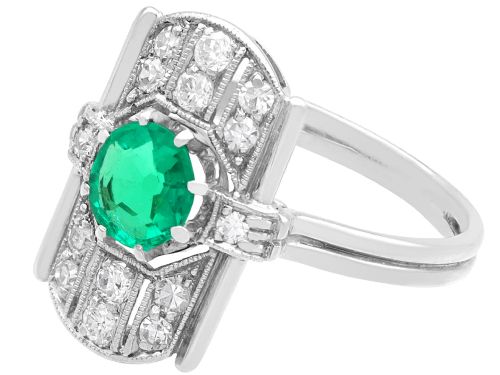 fig 3. An Art Deco 14ct white gold ring featuring a central round green emerald framed by geometric shoulders set with small brilliant diamonds.