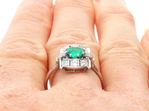 fig 8. An Art Deco 14ct white gold ring featuring a central round green emerald framed by geometric shoulders set with small brilliant diamonds.