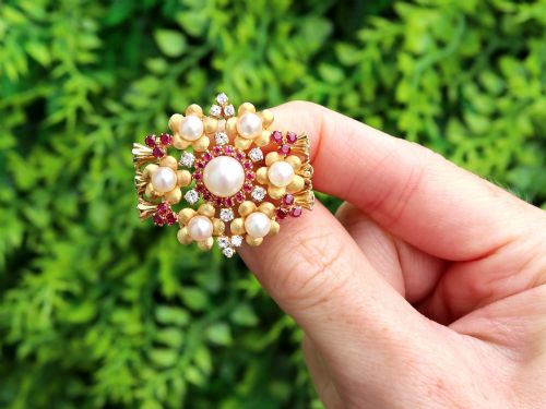 fig 1. An 18ct yellow gold floral cluster brooch set with a central pearl surrounded by small rubies, outer cultured pearls, round diamonds, and red rubies.