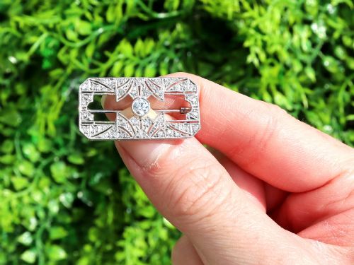 fig 1. A rectangular Art Deco 18ct white gold brooch featuring openwork geometric filigree, millegrain edging, and a central round-cut diamond.