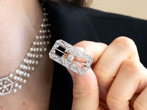 fig 3. A rectangular Art Deco 18ct white gold brooch featuring openwork geometric filigree, millegrain edging, and a central round-cut diamond.