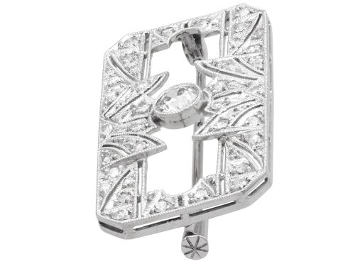 fig 6. A rectangular Art Deco 18ct white gold brooch featuring openwork geometric filigree, millegrain edging, and a central round-cut diamond.