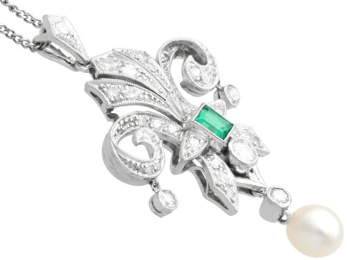 fig 7. An Art Deco platinum pendant shaped as a stylised fleur-de-lis, embellished with pave-set diamonds, a central rectangular emerald, and a hanging pearl drop.