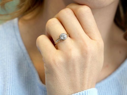 fig 3. An antique 15ct yellow gold solitaire ring featuring a bezel-set round diamond with decorative openwork shoulders.