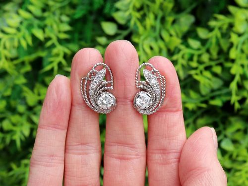 fig 1. A pair of Art Deco platinum earrings featuring round diamonds set within a textured rope-twist swirl design.