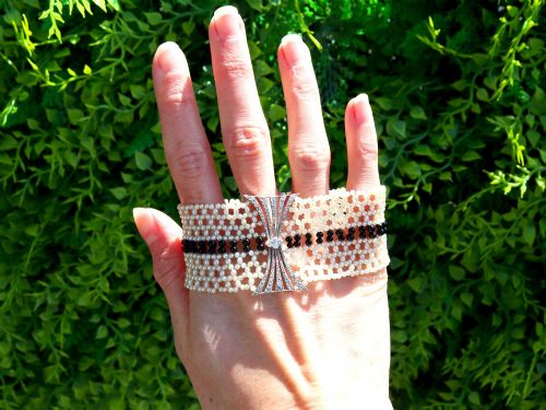 fig 1. An Art Deco multi-strand pearl and black onyx cuff bracelet featuring a central geometric bow-shaped platinum mount set with diamonds.