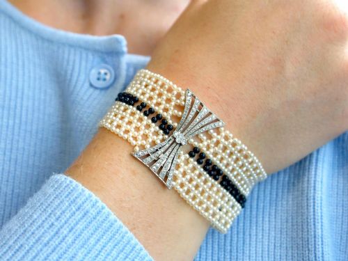fig 3. An Art Deco multi-strand pearl and black onyx cuff bracelet featuring a central geometric bow-shaped platinum mount set with diamonds.