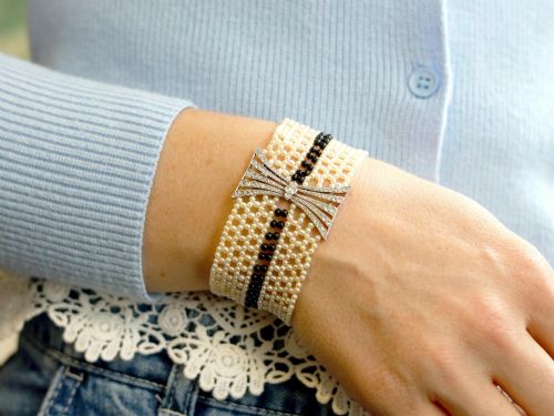 fig 4. An Art Deco multi-strand pearl and black onyx cuff bracelet featuring a central geometric bow-shaped platinum mount set with diamonds.