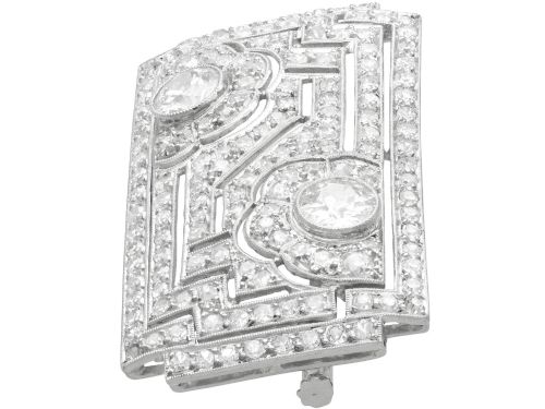 fig 4. A rectangular Art Deco platinum brooch featuring geometric openwork encrusted with round diamonds and two central bezel-set accent diamonds.