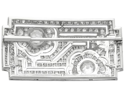 fig 6. A rectangular Art Deco platinum brooch featuring geometric openwork encrusted with round diamonds and two central bezel-set accent diamonds.