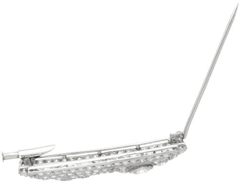 fig 7. A rectangular Art Deco platinum brooch featuring geometric openwork encrusted with round diamonds and two central bezel-set accent diamonds.