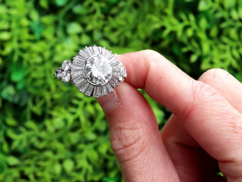 fig 1. An Art Deco platinum ballerina ring featuring a prominent round central diamond surrounded by a radiating halo of tapered baguette cut diamonds.