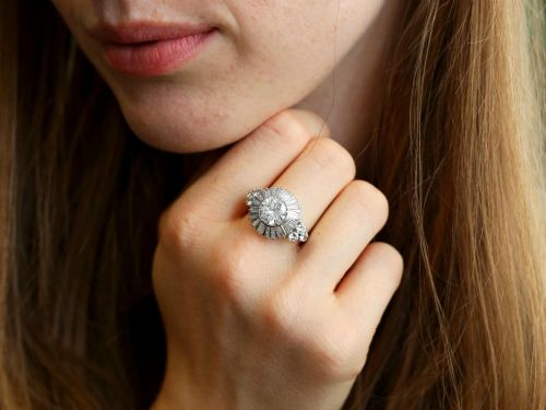fig 4. An Art Deco platinum ballerina ring featuring a prominent round central diamond surrounded by a radiating halo of tapered baguette cut diamonds.