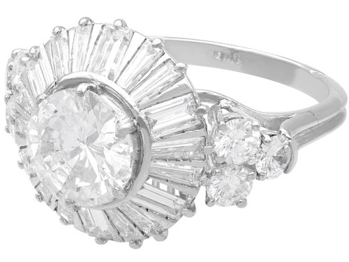 fig 5. An Art Deco platinum ballerina ring featuring a prominent round central diamond surrounded by a radiating halo of tapered baguette cut diamonds.