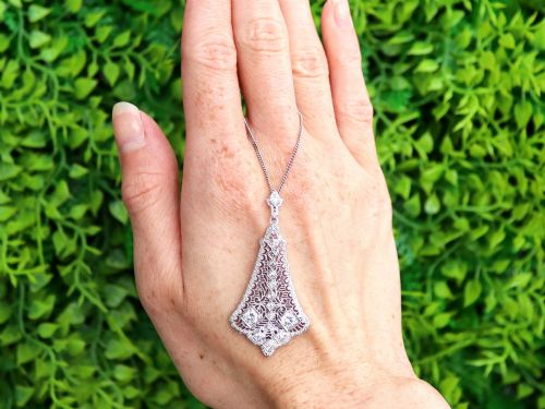 fig 1. An Art Deco 14ct white gold pendant featuring geometric pierced filigree lattice work set with multiple diamonds suspended from a chain.