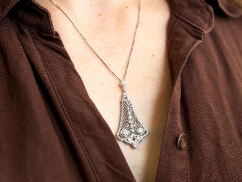fig 2. An Art Deco 14ct white gold pendant featuring geometric pierced filigree lattice work set with multiple diamonds suspended from a chain.
