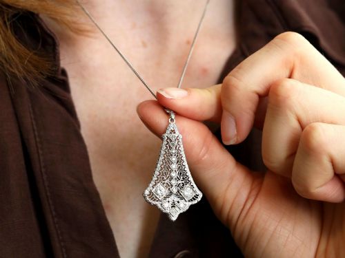 fig 3. An Art Deco 14ct white gold pendant featuring geometric pierced filigree lattice work set with multiple diamonds suspended from a chain.