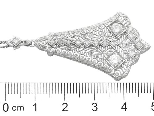 fig 9. An Art Deco 14ct white gold pendant featuring geometric pierced filigree lattice work set with multiple diamonds suspended from a chain.