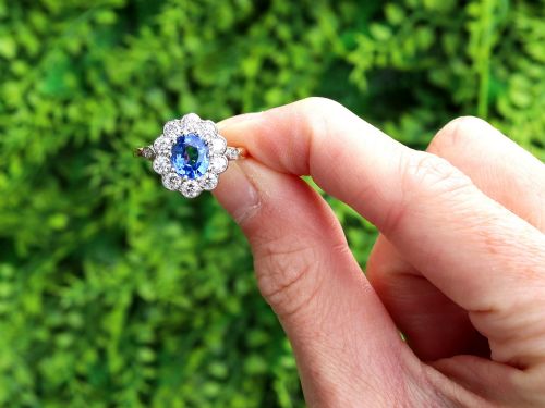 fig 1. An 18ct yellow gold cluster ring featuring an oval blue sapphire surrounded by a halo of round diamonds set in platinum.