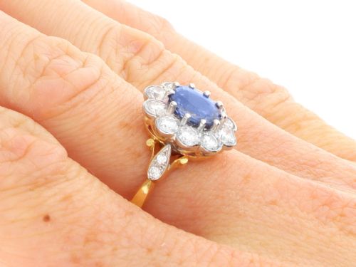 fig 9. An 18ct yellow gold cluster ring featuring an oval blue sapphire surrounded by a halo of round diamonds set in platinum.