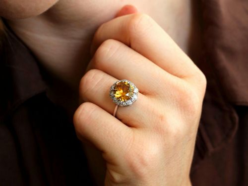 fig 2. An antique Art Deco platinum ring featuring a central round orange zircon surrounded by a halo of claw-set diamonds.