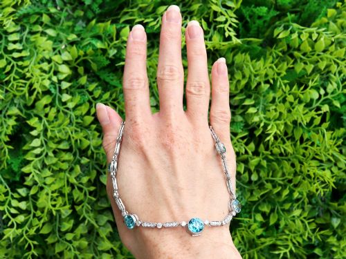 fig 1. An Art Deco platinum chain necklace featuring five bezel-set round blue zircons separated by geometric diamond-set bar links.