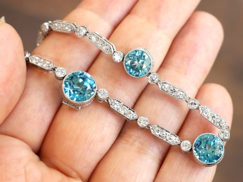 fig 3. An Art Deco platinum chain necklace featuring five bezel-set round blue zircons separated by geometric diamond-set bar links.