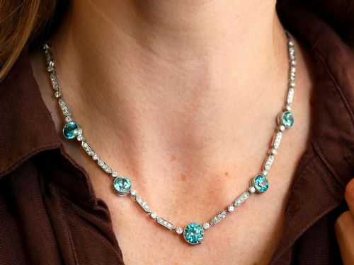 fig 5. An Art Deco platinum chain necklace featuring five bezel-set round blue zircons separated by geometric diamond-set bar links.