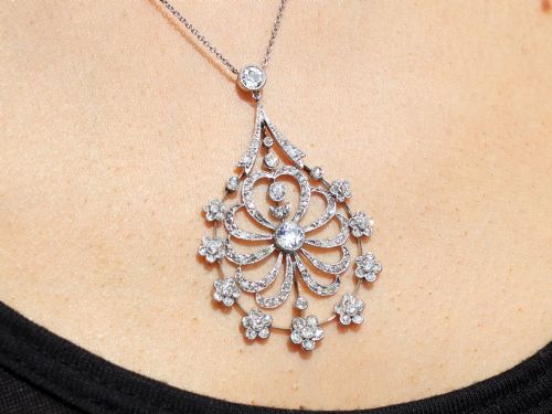 fig 9. An antique Edwardian openwork platinum pendant set with diamonds in a teardrop silhouette with floral motifs, suspended from a fine chain.