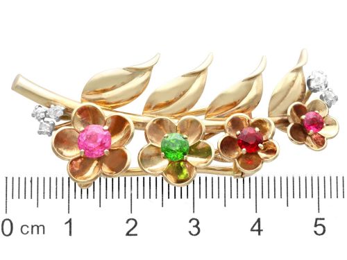 fig 9. An antique 9ct yellow gold floral spray brooch featuring four carved flower heads set with colourful gemstones and diamond accents.