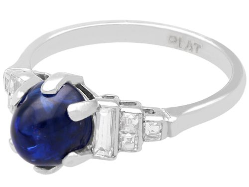 fig 5. An Art Deco platinum dress ring set with a central oval cabochon blue sapphire flanked by stepped geometric shoulders of baguette cut diamonds.