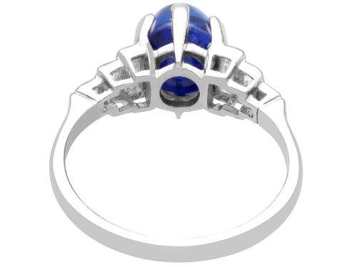 fig 6. An Art Deco platinum dress ring set with a central oval cabochon blue sapphire flanked by stepped geometric shoulders of baguette cut diamonds.
