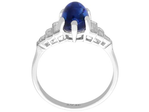 fig 7. An Art Deco platinum dress ring set with a central oval cabochon blue sapphire flanked by stepped geometric shoulders of baguette cut diamonds.