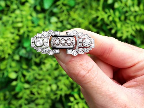 fig 1. An Art Deco platinum brooch featuring geometric stepped motifs, diamond pave setting, central lattice detail, and black enamel accents.