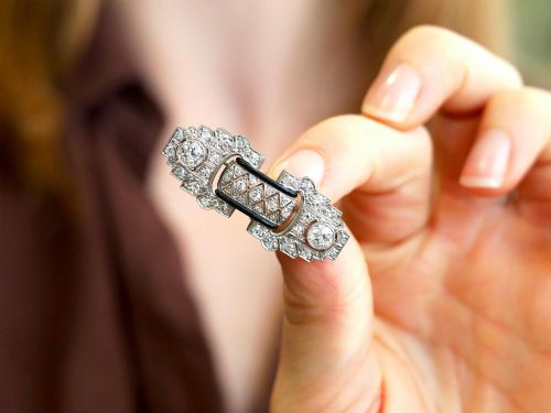 fig 3. An Art Deco platinum brooch featuring geometric stepped motifs, diamond pave setting, central lattice detail, and black enamel accents.