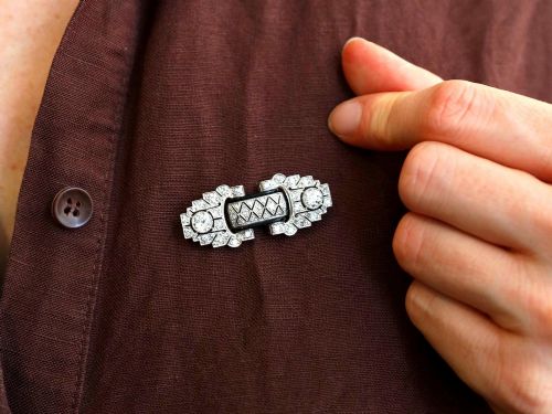 fig 4. An Art Deco platinum brooch featuring geometric stepped motifs, diamond pave setting, central lattice detail, and black enamel accents.