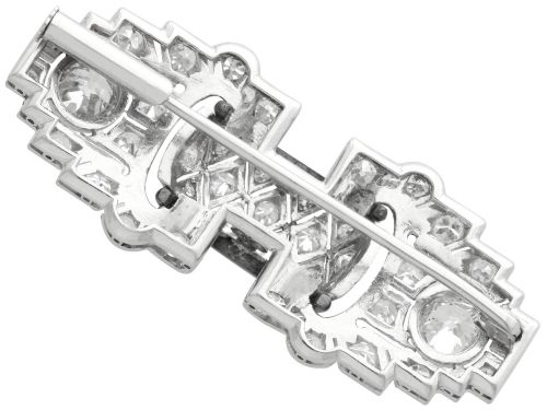 fig 8. An Art Deco platinum brooch featuring geometric stepped motifs, diamond pave setting, central lattice detail, and black enamel accents.