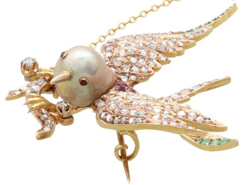 fig 5. An antique Victorian 18ct yellow gold bird brooch set with diamonds on the wings, emeralds along the outer feathers, a natural pearl body, and ruby details.