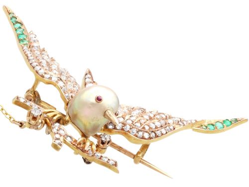 fig 6. An antique Victorian 18ct yellow gold bird brooch set with diamonds on the wings, emeralds along the outer feathers, a natural pearl body, and ruby details.