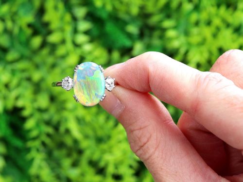 fig 1. An antique platinum trilogy ring featuring a central oval cabochon opal flanked by two round cut diamonds.