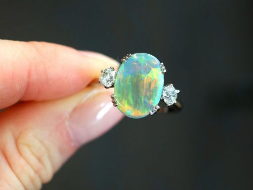 fig 3. An antique platinum trilogy ring featuring a central oval cabochon opal flanked by two round cut diamonds.