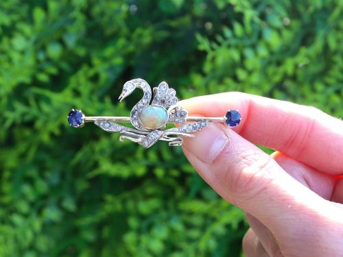 fig 1. An antique Victorian 9ct gold bar brooch featuring a central swan motif set with diamonds and an oval opal body, flanked by two blue sapphires.
